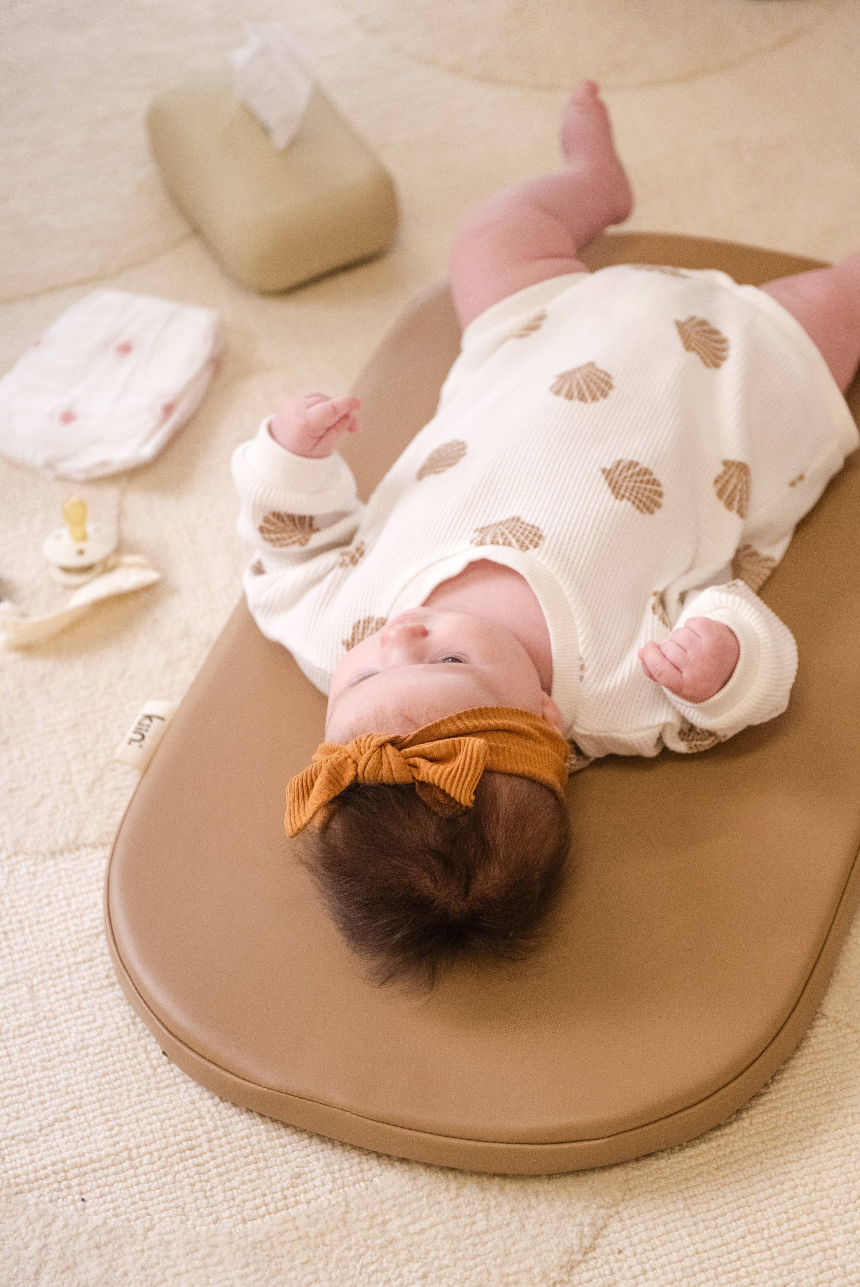 Baby lying on a wipeable change pad with a white blanket and pink socks in the background