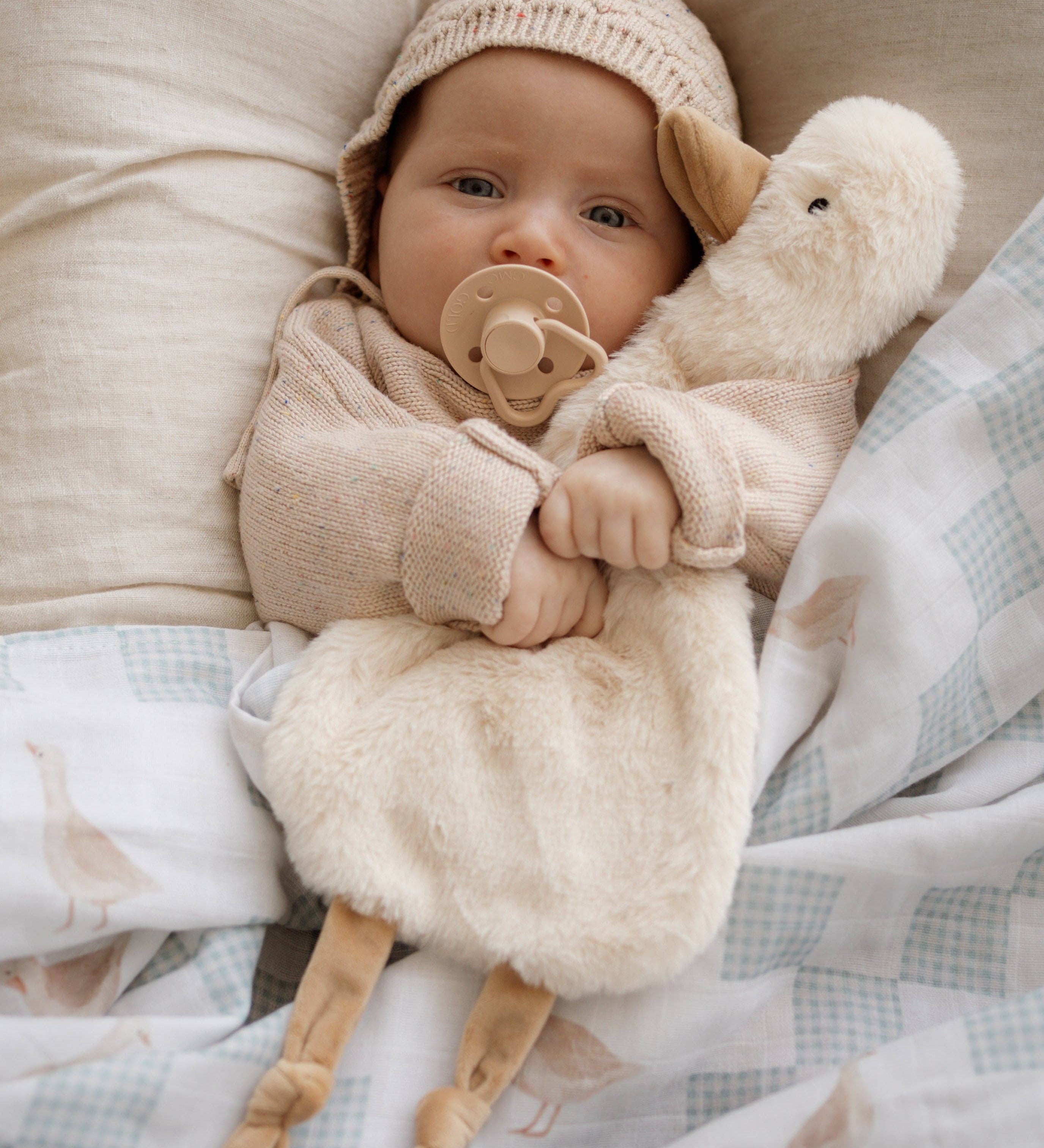 Baby in a cozy setting with Quacks the Comforter Toy