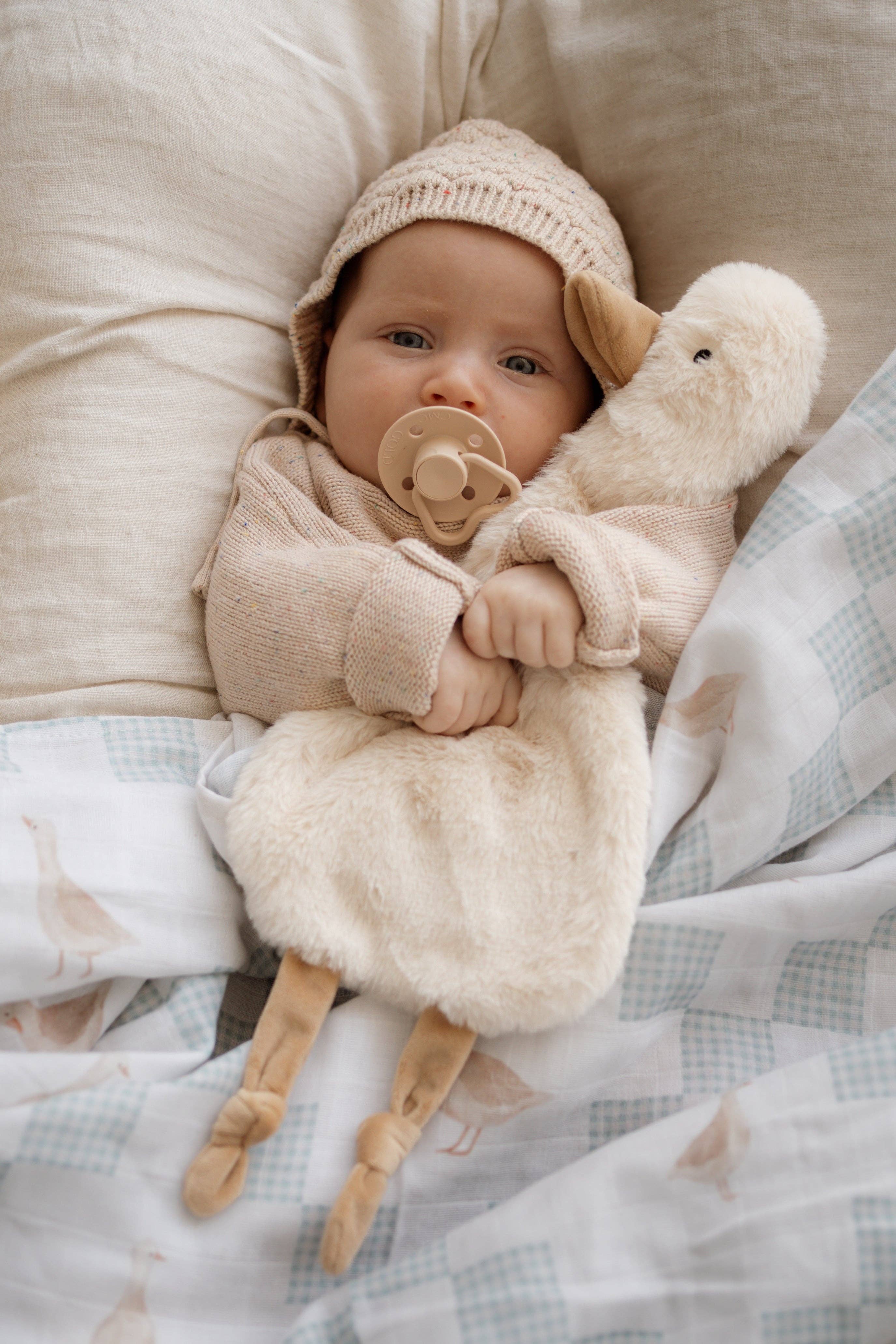 Baby in a cozy setting with Quacks the Comforter Toy