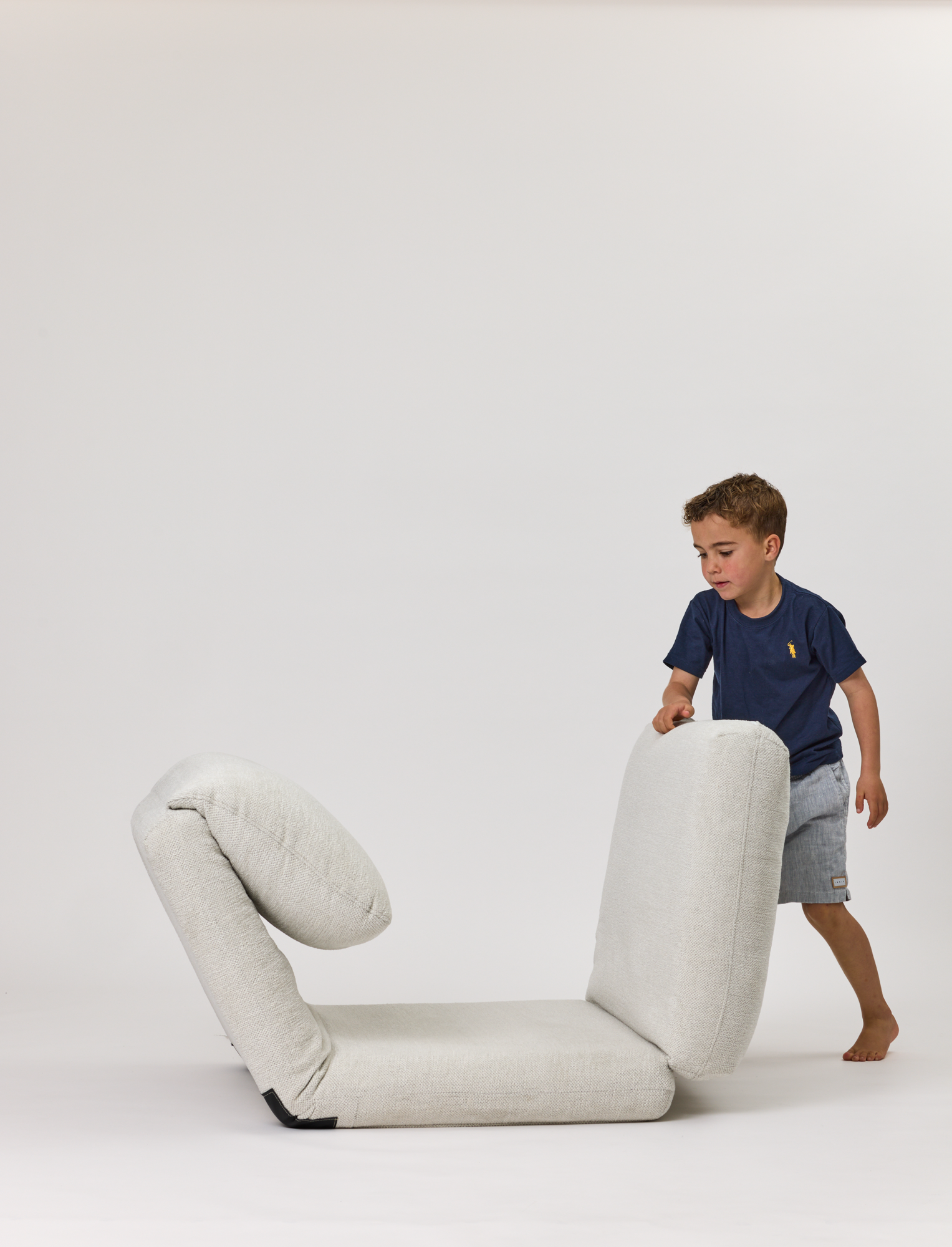 Child playing with a Rylee Recliner on a white background