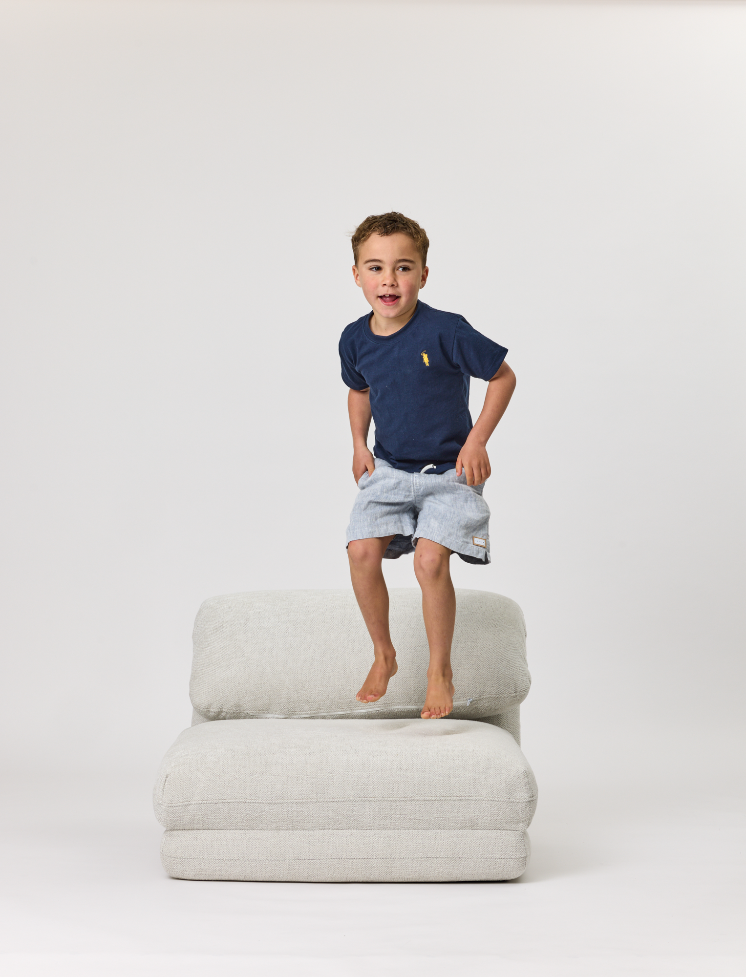 Child standing on a Rylee Recliner on a white background