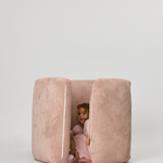 Child peeking out from a pink Rylee Recliner on a white background