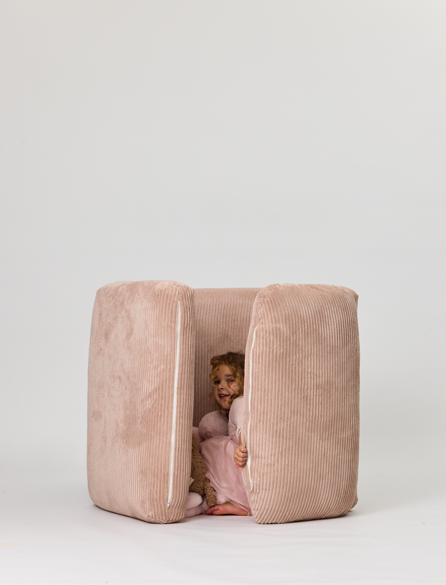 Child peeking out from a pink Rylee Recliner on a white background
