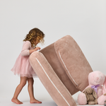 Child in a pink dress interacting with a Rylee Recliner on a white background