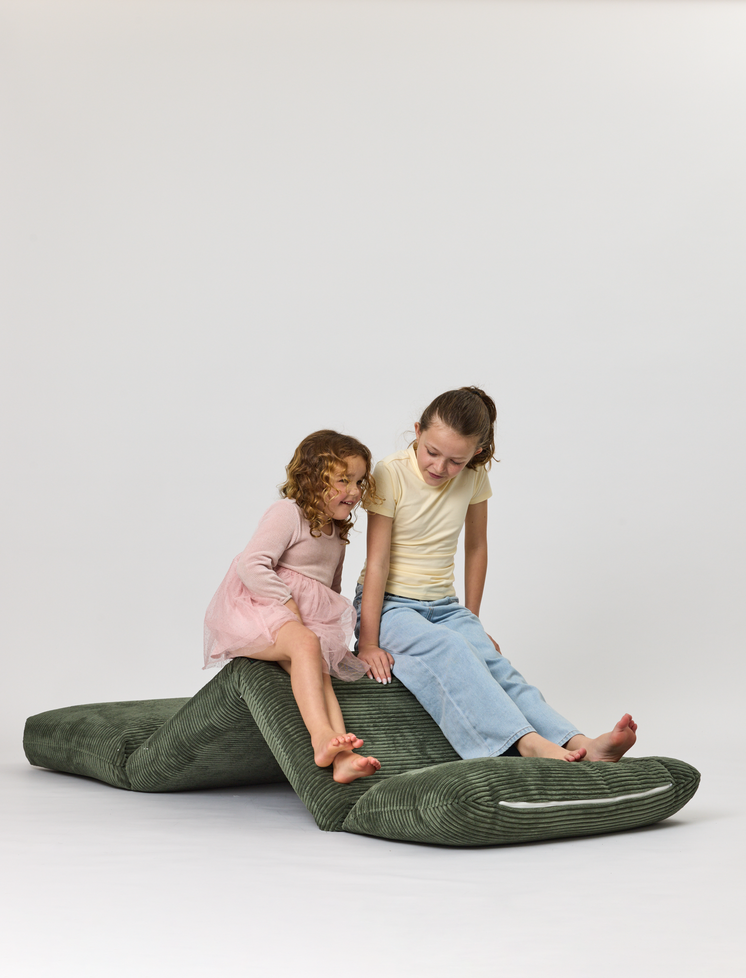 Two children sitting on a Forest Rylee Recliner on a white background
