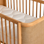 Indi Cot with a textured mattress cover on a white background