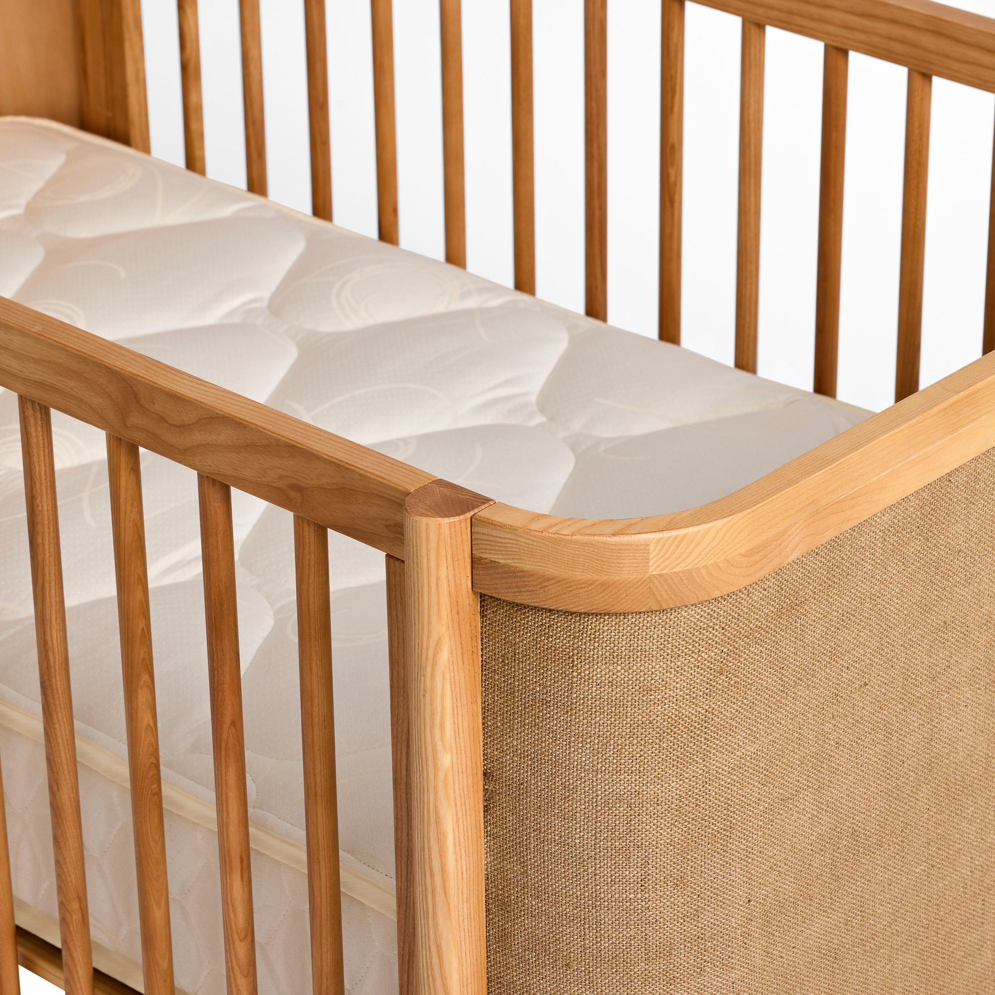 Indi Cot with a textured mattress cover on a white background