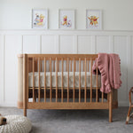 Indi Cot with pink blanket in a nursery with Winnie the Pooh posters on the wall.