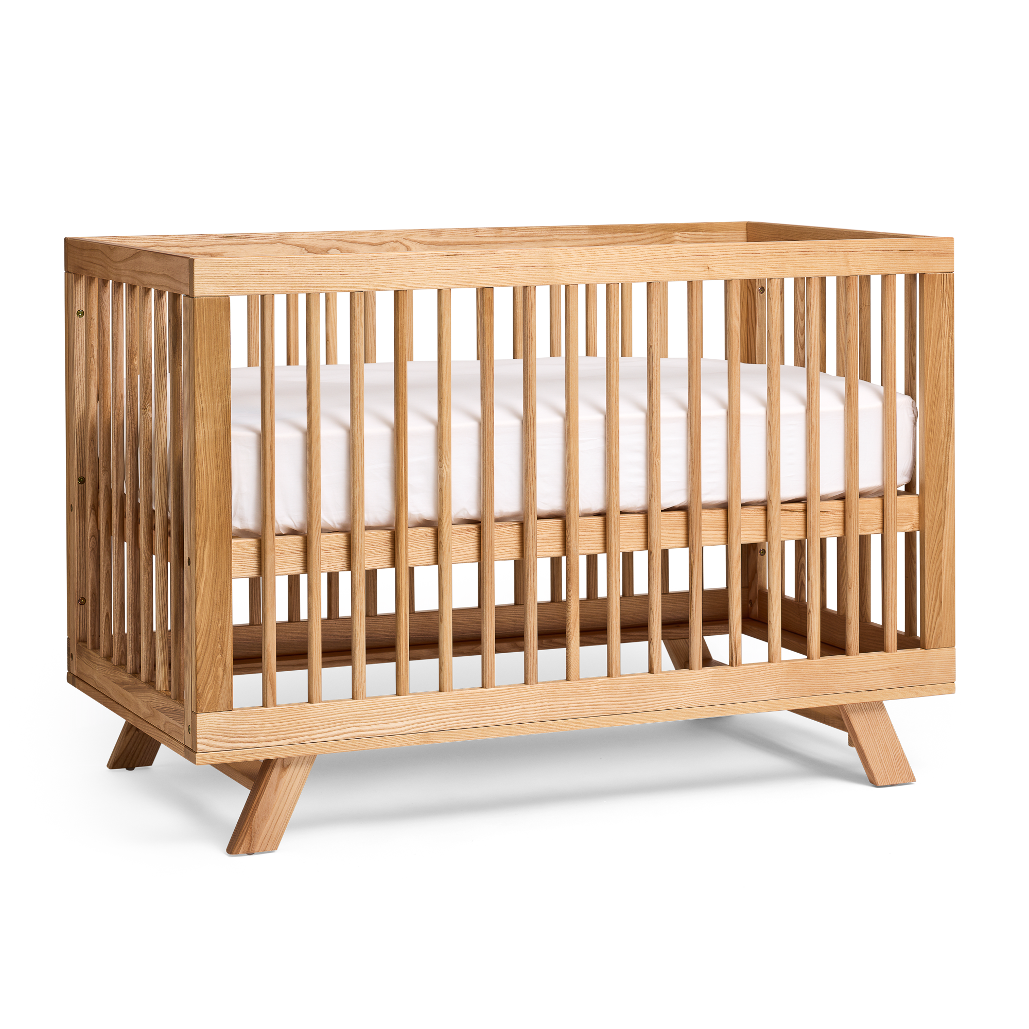 MacKenzie Cot in natural timber with splayed legs and slatted sides, angled view on a plain background