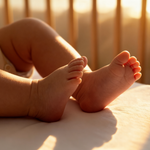 Feet of a baby lying on a mattress in the MacKenzie Cot.