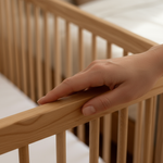 Hand touching a MacKenzie Cot rail with a blurred background