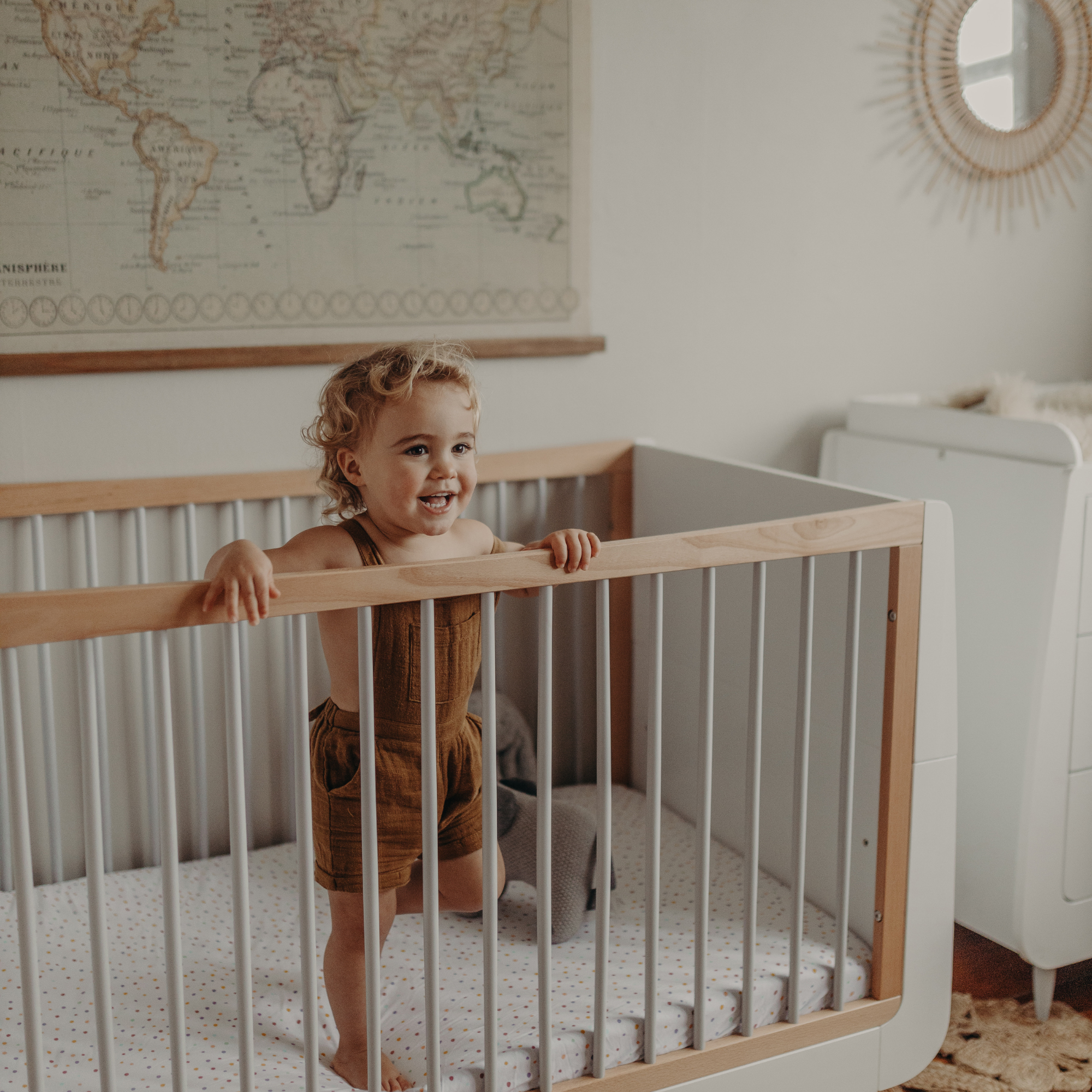 Child standing in a cot with SnuzKot bedding